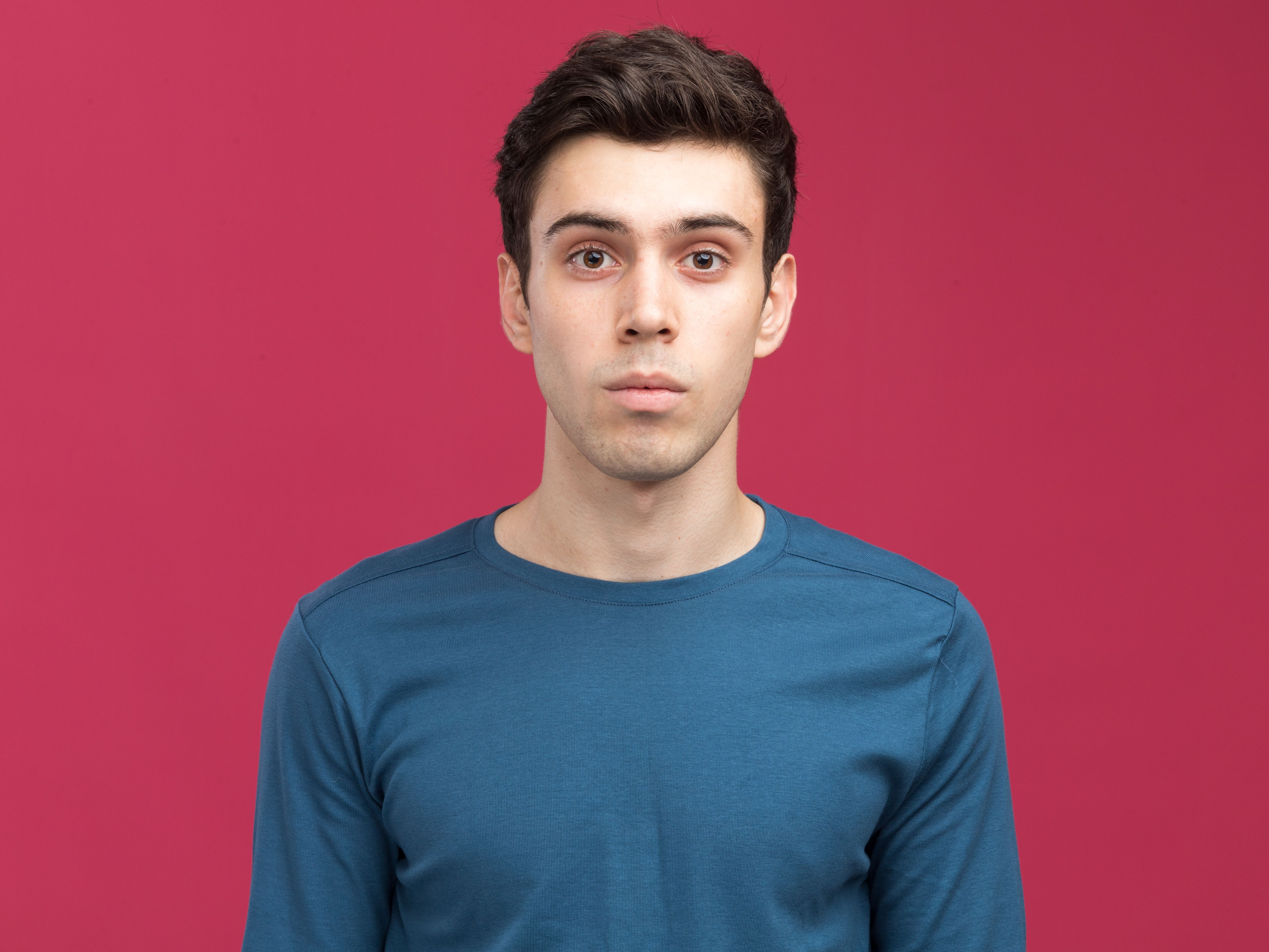 impressed young brunette caucasian boy looking camera pink